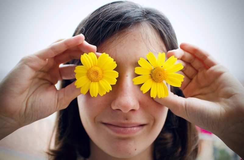 Girl with flowers over eyes.