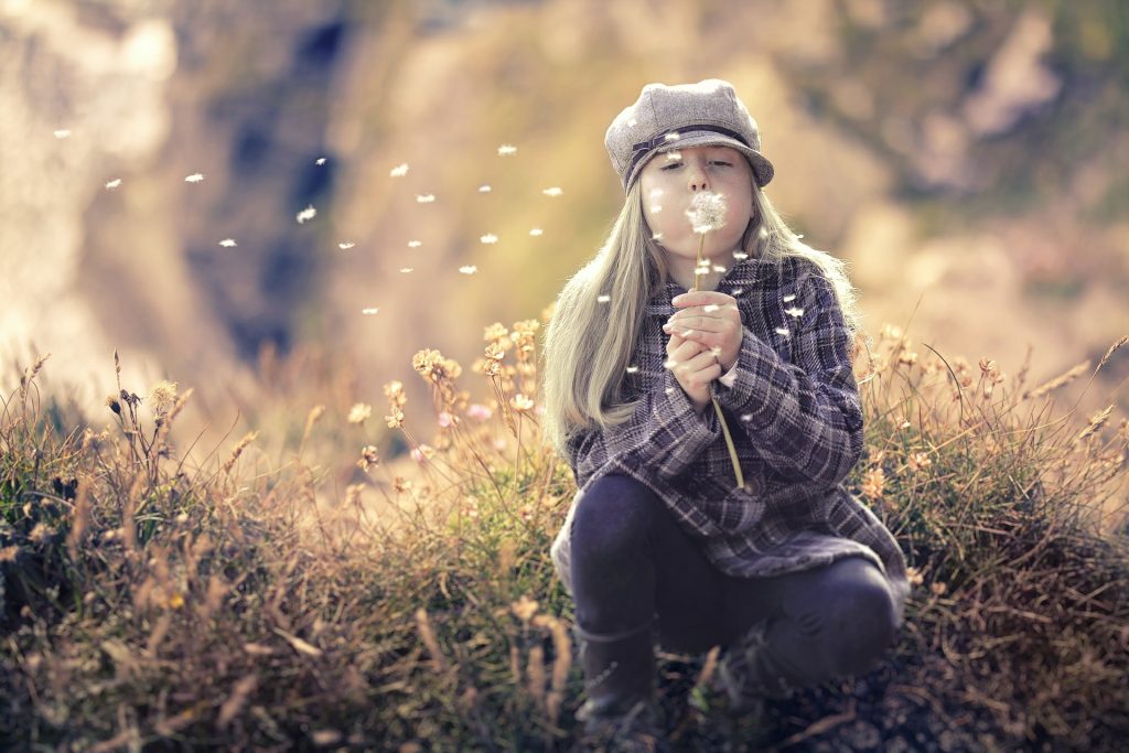 Girl blowing flower seeds.